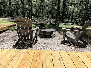 A deck with Adirondack chairs and a circular fire pit. - Family friendly dual-cabin in Sam Houston National Forest (Cleveland)