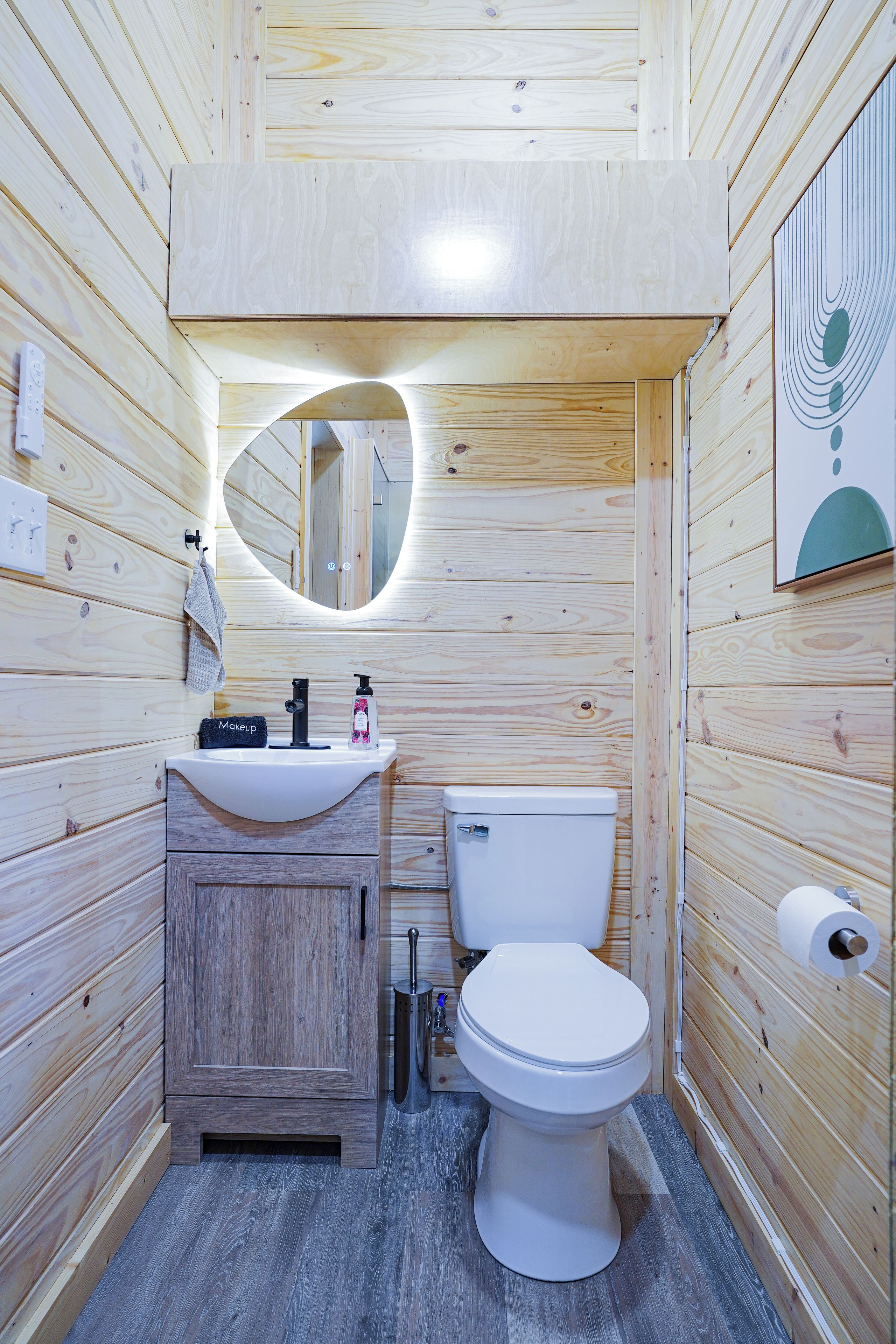 Un baño de madera pequeño y acogedor con un inodoro blanco, un lavabo y un espejo.