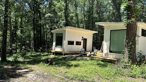 Une cabane dotée d’une terrasse, d’une grande fenêtre et d’une porte.