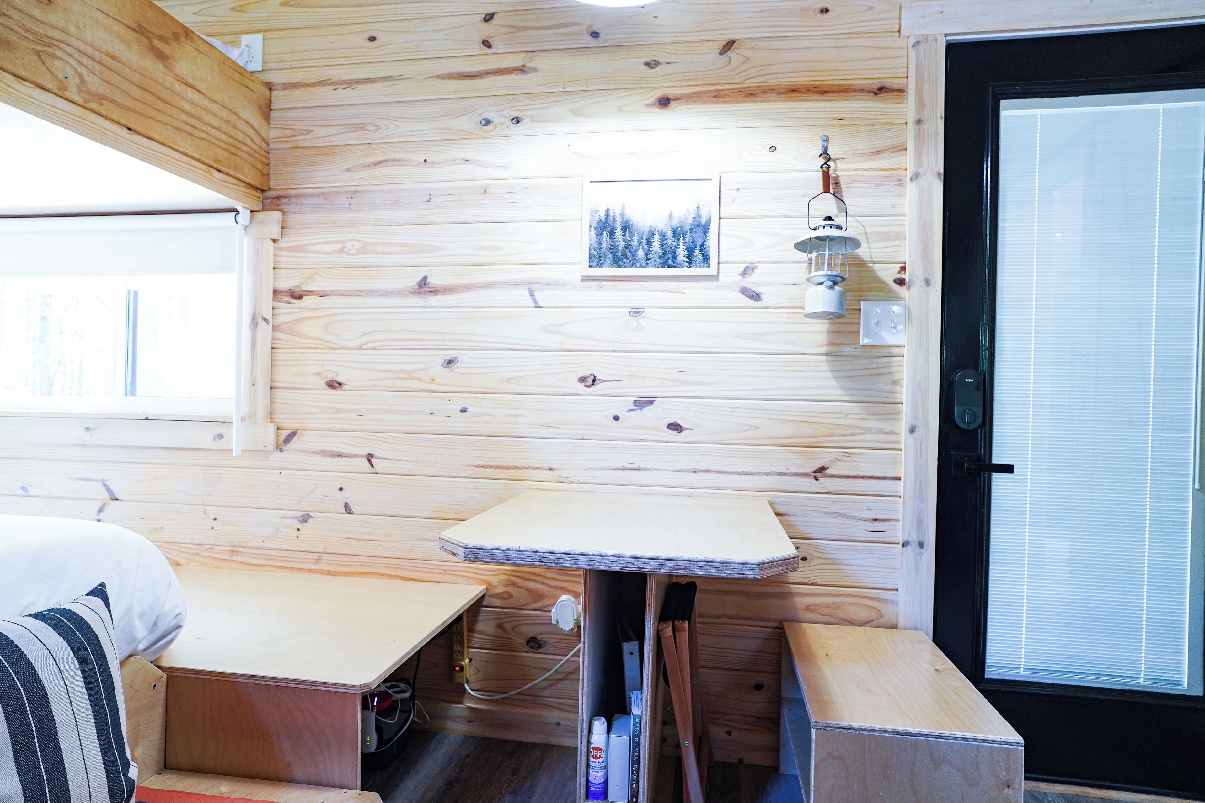A wooden interior with a bed, a table, and a door.