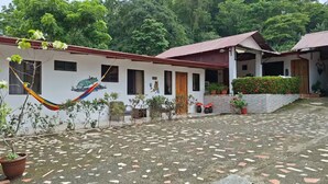 A building with a tiled patio, a hammock, and potted plants. - Villa Ensueño Cahuita 2 familiar (Westfalia)
