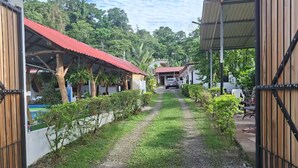 A pathway leading to a building with a red roof, surrounded by greenery and a clear sky. - Villa Ensueño Cahuita 2 familiar (Westfalia)