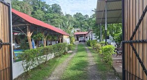 A pathway leading to a building with a red roof, surrounded by greenery and a clear sky. - Villa Ensueño Cahuita 2 familiar (Westfalia)