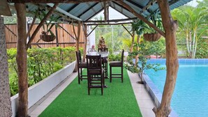 A covered outdoor area with a pool, a table with chairs, and greenery. - Villa Ensueño Cahuita 2 familiar (Westfalia)