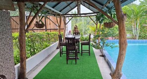 A covered outdoor area with a pool, a table with chairs, and greenery. - Villa Ensueño Cahuita 2 familiar (Westfalia)