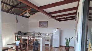 A kitchen with a dining area, wooden flooring, and a ceiling with exposed beams. - Alojamientos Ensueño Cahuita 1 (Westfalia)