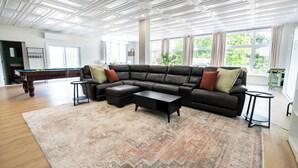 A living room with a sectional sofa, a pool table, and a large window with curtains. - Souvenir  (Chelsea)