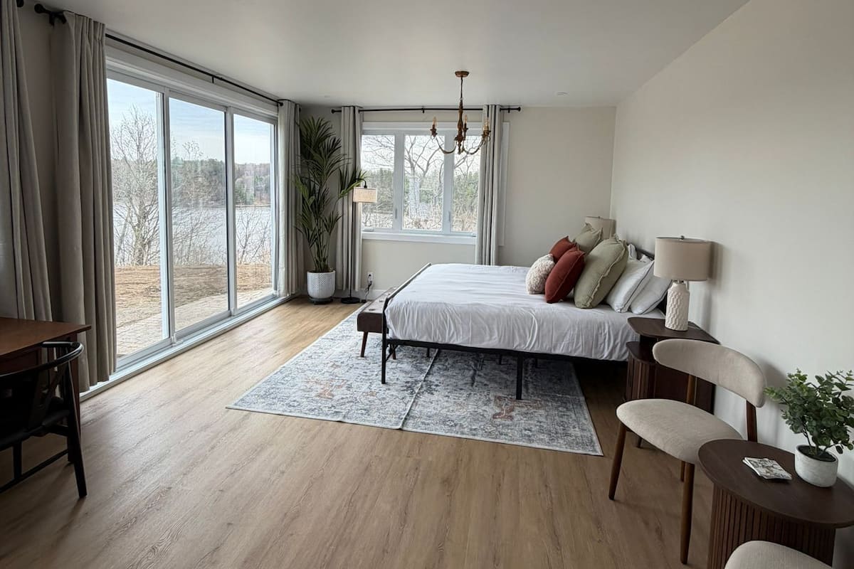 A modern bedroom with a large bed, a desk, and a chair.