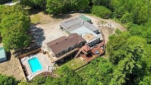 Una casa grande con piscina, terraza y porche cubierto.