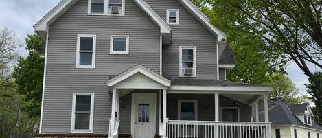 A two-story house with a front porch, stone foundation, and a garage.