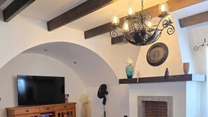 Un salon comprenant un téléviseur, un canapé, une table basse, une cheminée et des objets de décoration.