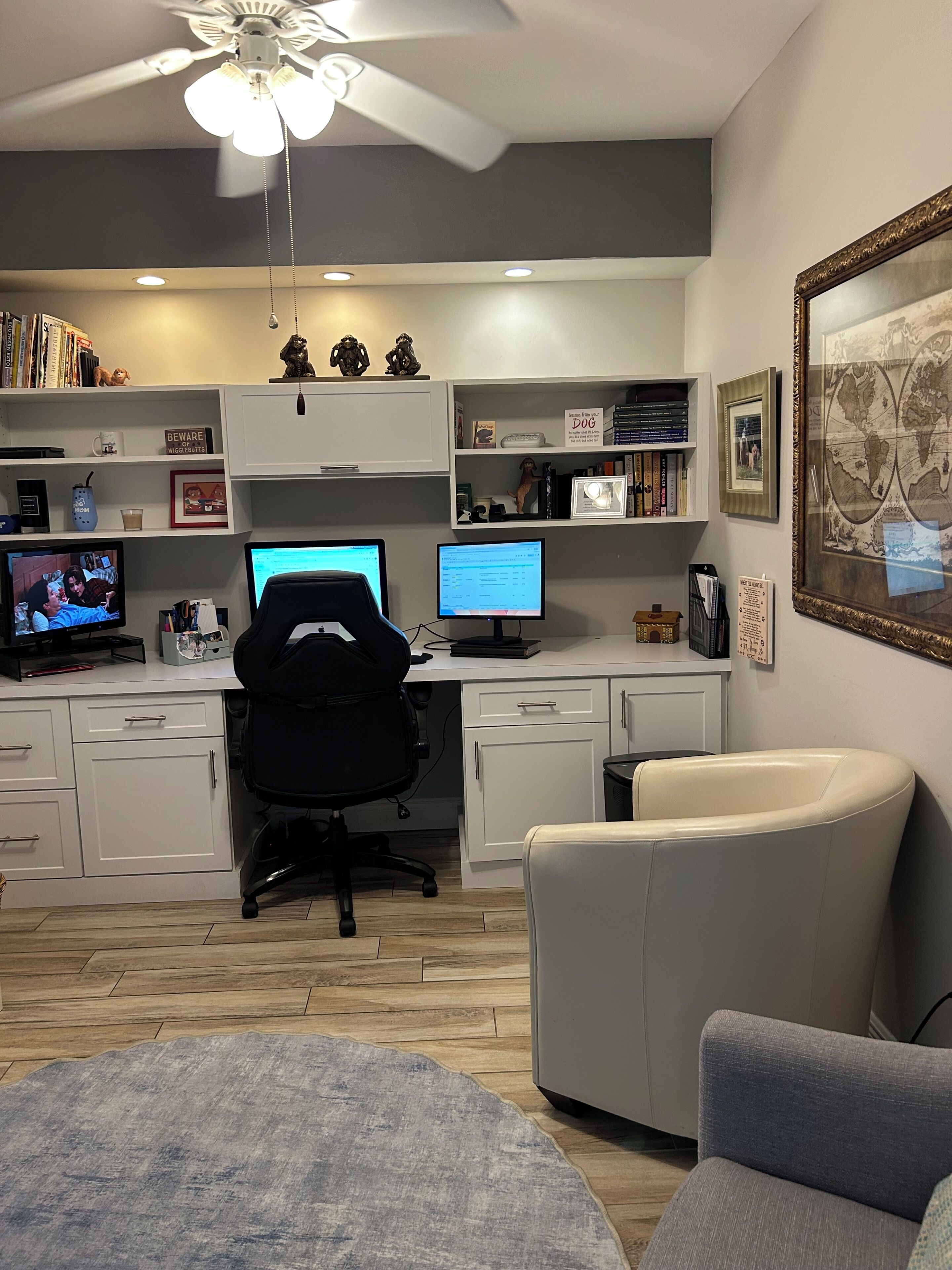 A home office with a desk, two monitors, a chair, and a ceiling fan.