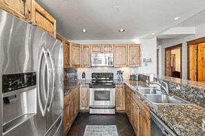 Una cocina moderna con electrodomésticos de acero inoxidable, armarios de madera y encimeras de granito, además de un horno empotrado.