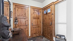 A corner room with wooden doors, a stone sculpture, a bench, and a patterned rug. - Traverse Hospitality (Crested Butte)