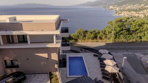 Un edifici modern amb piscina al terrat, zona d'estar a l'aire lliure i vista al mar.