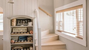 Een trap met een houten leuning, een witte muur en een raam met zonwering.