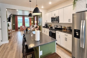 A modern kitchen with white cabinets, stainless steel appliances, and a central island with a sink and bar stools.
