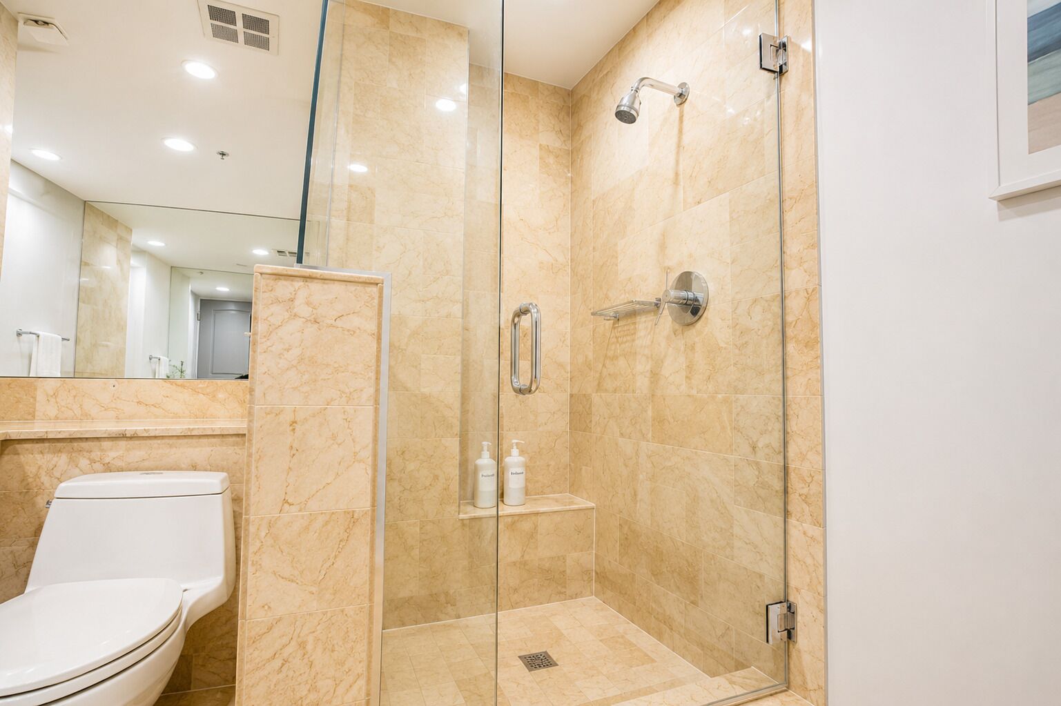 Une salle de bain moderne avec une douche à parois de verre, des toilettes et un miroir.