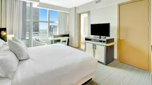 A hotel room with a bed, a desk, a television, and a door.