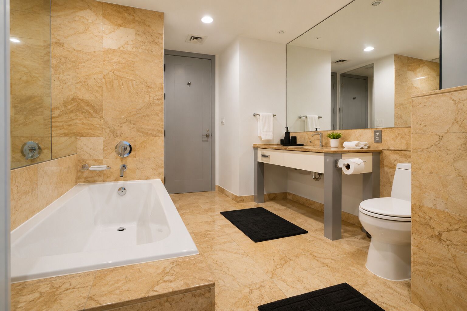 A modern bathroom with a bathtub, toilet, and sink, featuring marble flooring and a large mirror.