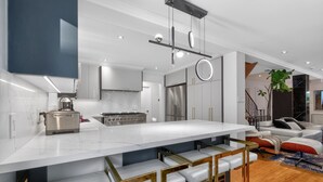 A modern kitchen with a large island, stainless steel appliances, and a bar area with stools. - Luxury Executive Home Near Airport & Downtown (Toronto)