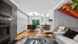 A modern living room with a fireplace, a dining area, and a kitchen with white cabinets. - Luxury Executive Home Near Airport & Downtown (Toronto)
