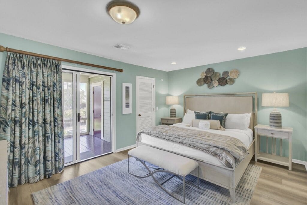 A bedroom with a bed, bench, nightstands, and a view through a sliding door.