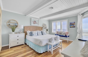 A bedroom with a bed, bedside tables, a bench, a window with shutters, and a view of the ocean. - Wild Dunes Vacation Condos 1&2 Bedrooms (Isle of Palms)