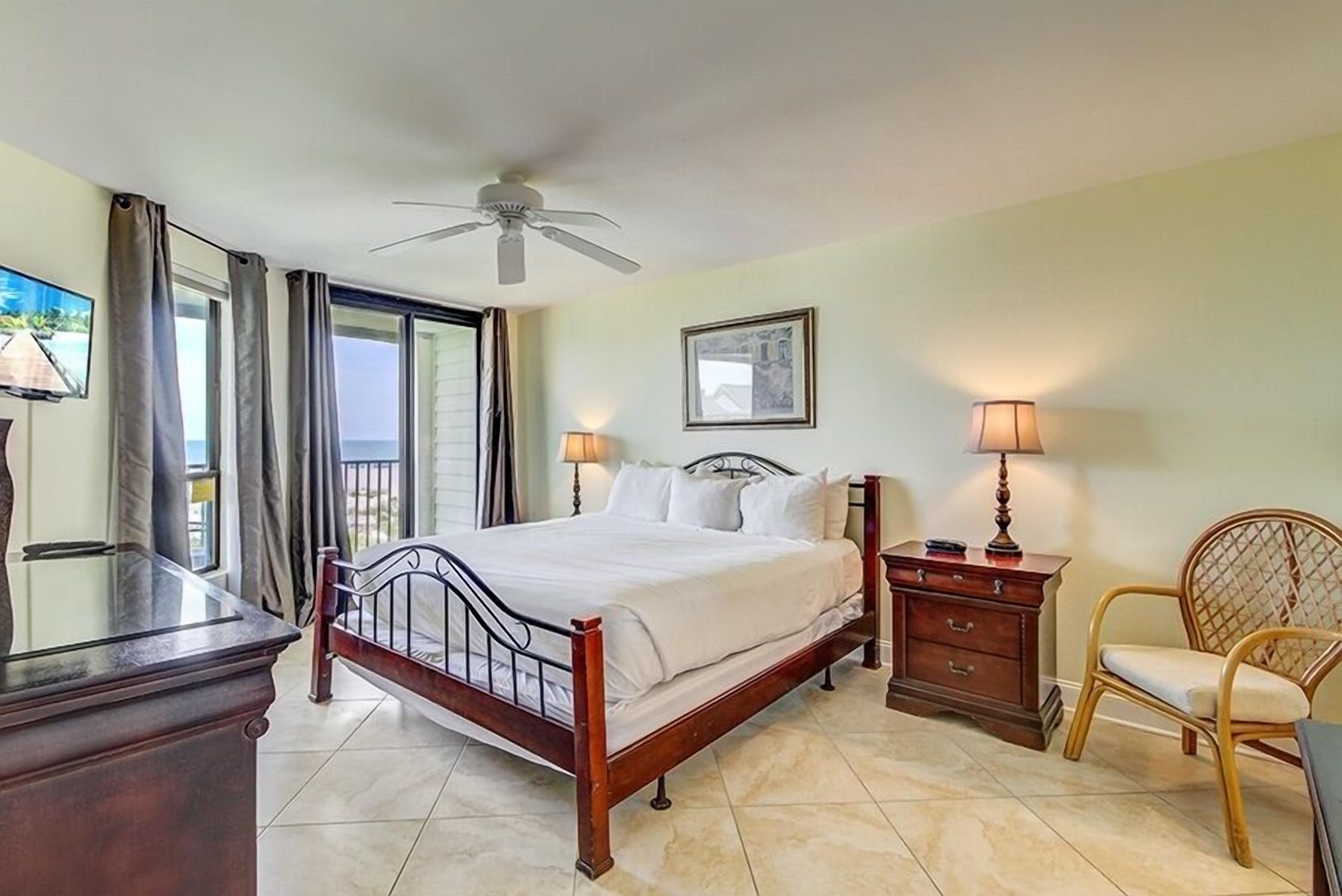 A bedroom with a bed, a ceiling fan, a nightstand, a chair, and a TV.