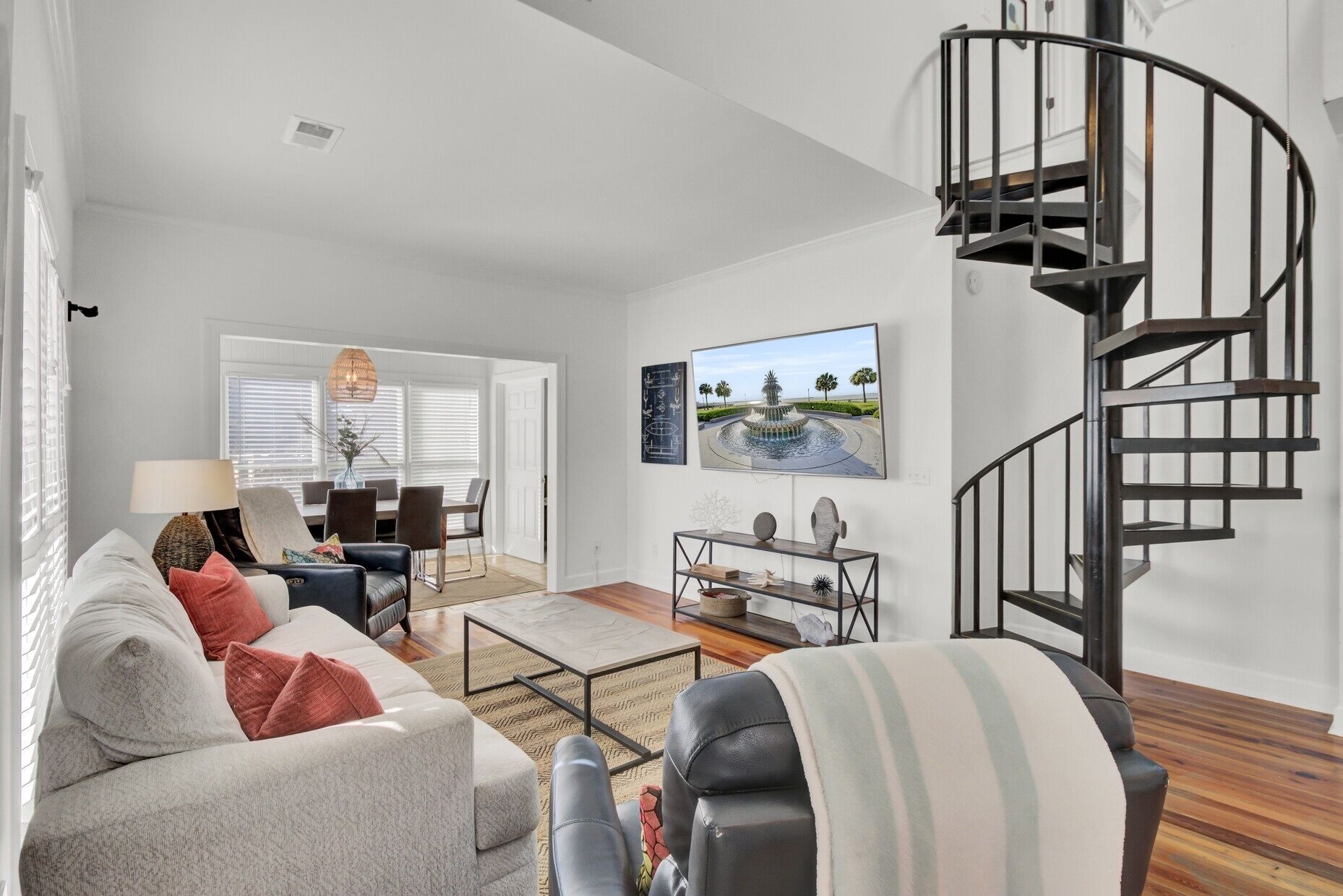 A modern living room with a sofa, coffee table, and a spiral staircase.