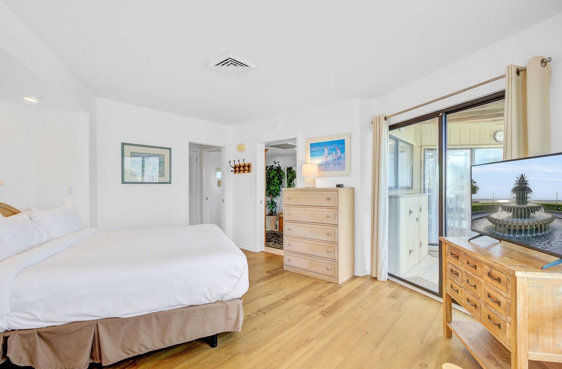 A bedroom with a bed, dresser, and a view of a fountain through a glass door.