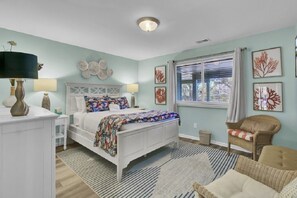 A bedroom with a bed, bedside tables, a chair, a window with curtains, and wall art. - Wild Dunes Vacation Condos 1&2 Bedrooms (Isle of Palms)