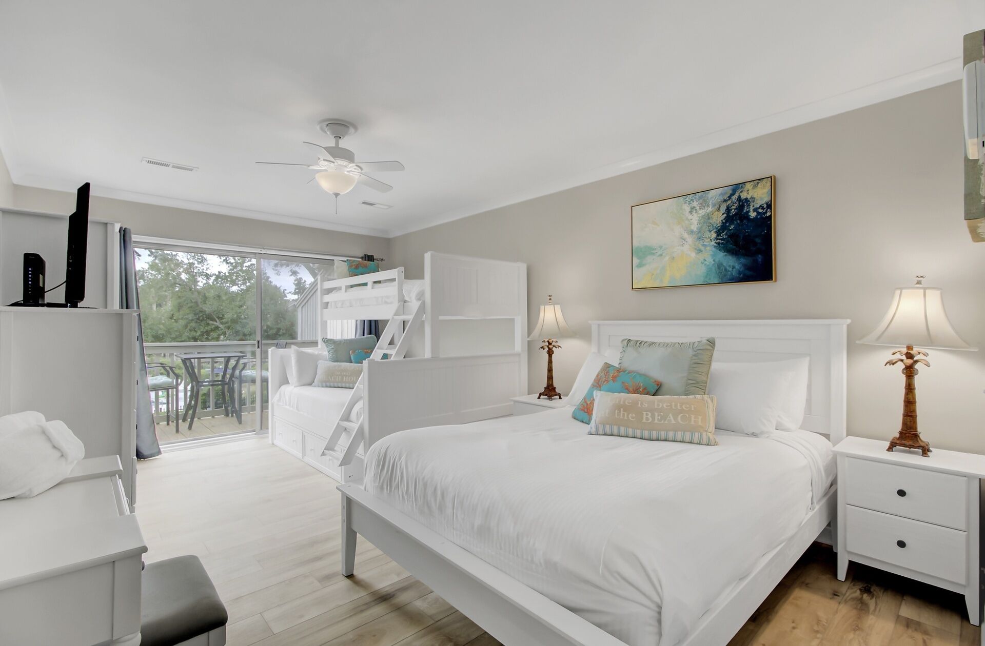 A bedroom with a bed, bedside tables, a ceiling fan, a window, and a balcony.
