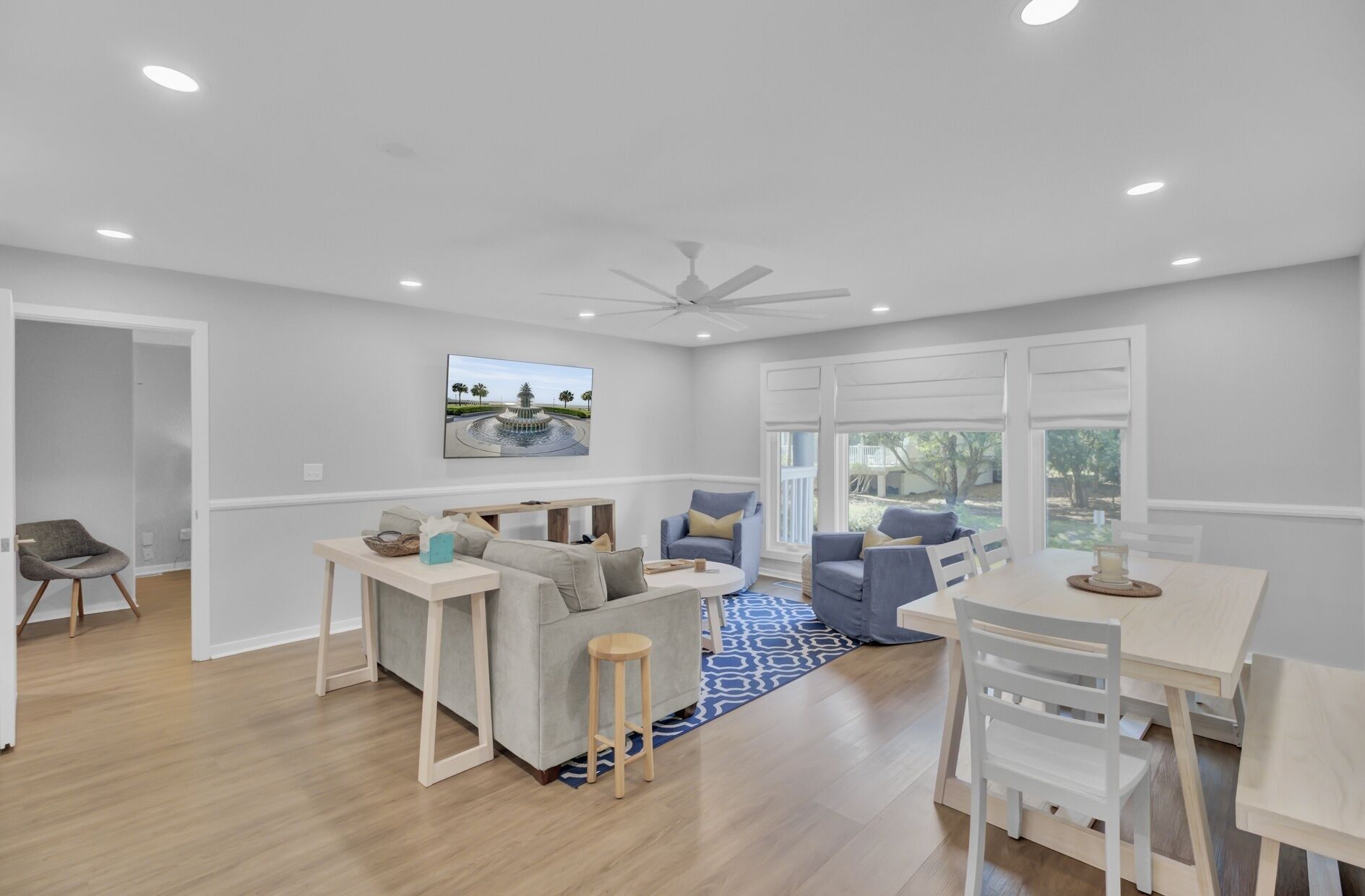 A spacious living area with a ceiling fan, a dining table, and a sofa set.