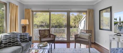 A spacious living room with a sofa, armchairs, a coffee table, and a television.