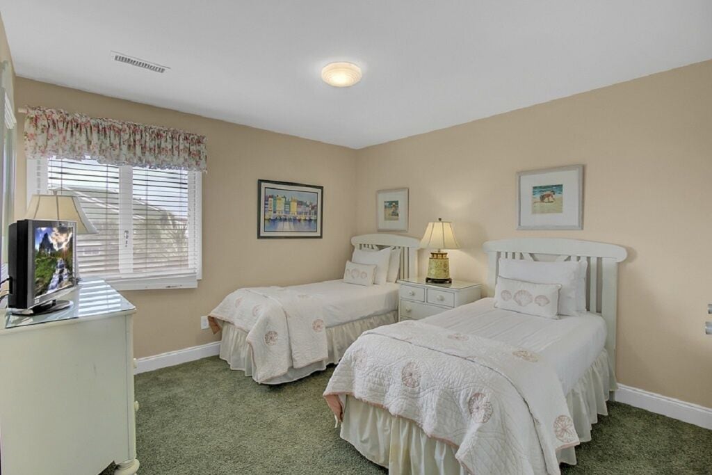 A bedroom with two beds, a TV, and a lamp.