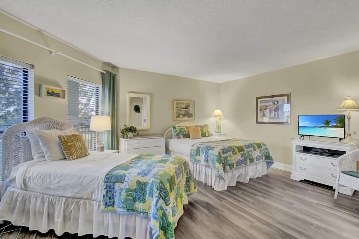 A bedroom with two beds, a TV, and a dresser.