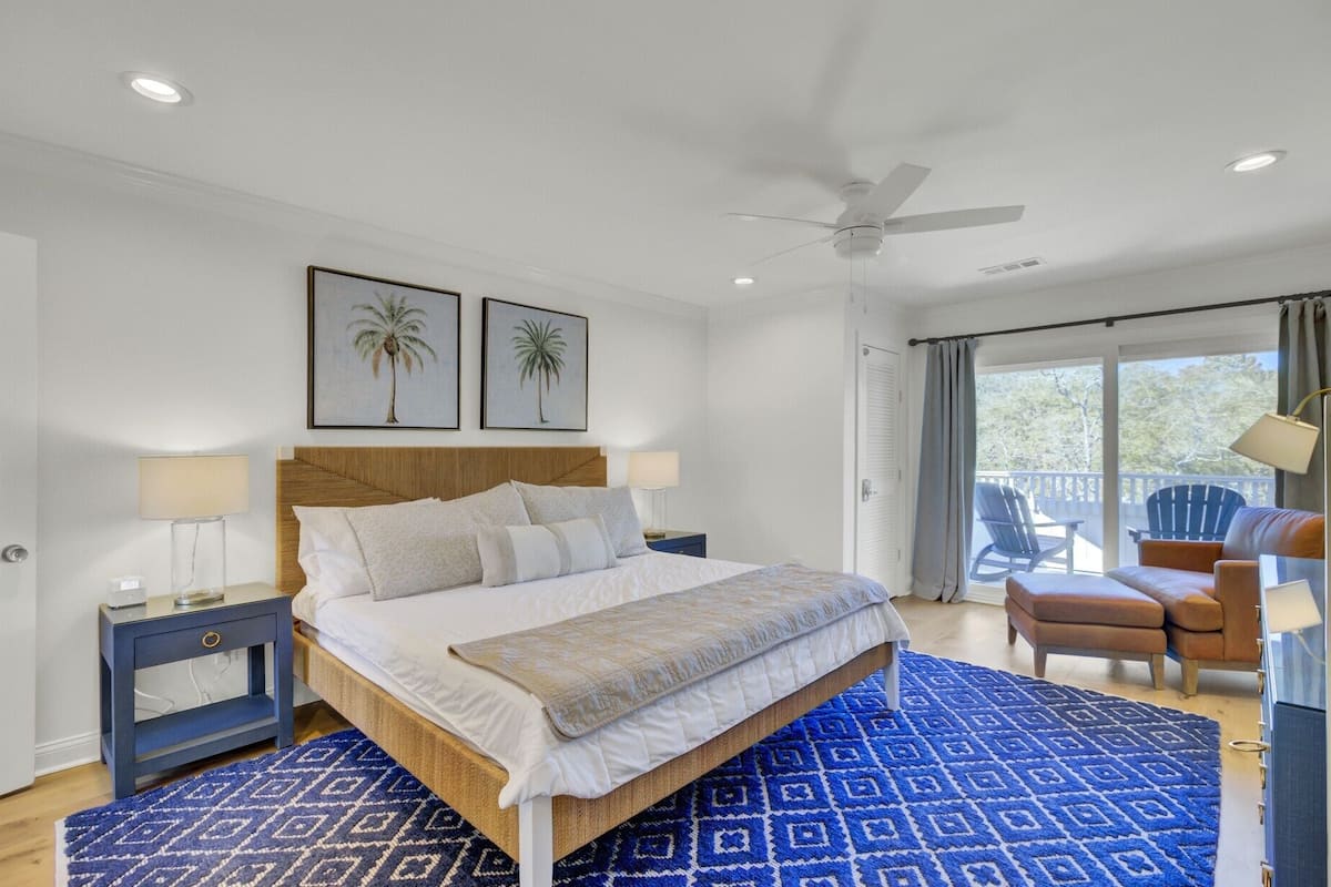 Un dormitorio con cama, mesitas de noche, ventilador de techo y vistas al exterior.