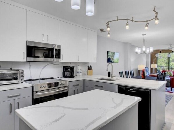 A modern kitchen with white cabinetry, a built-in microwave, a toaster, and a dishwasher. - Wild Dunes Vacation Condos 3&4 Bedrooms (Isle of Palms)