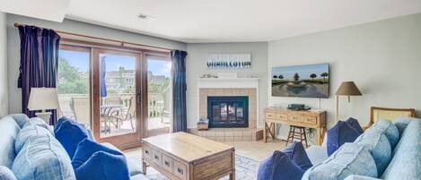 Una sala de estar con chimenea, televisor y vistas al exterior.