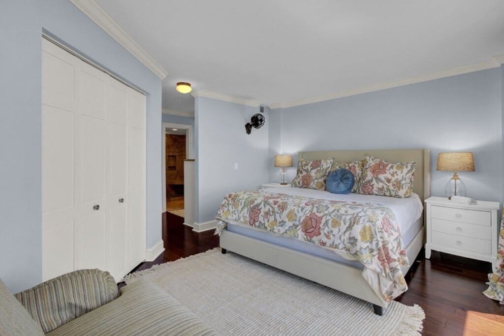 A bedroom with a bed, nightstands, a door, and a hallway.