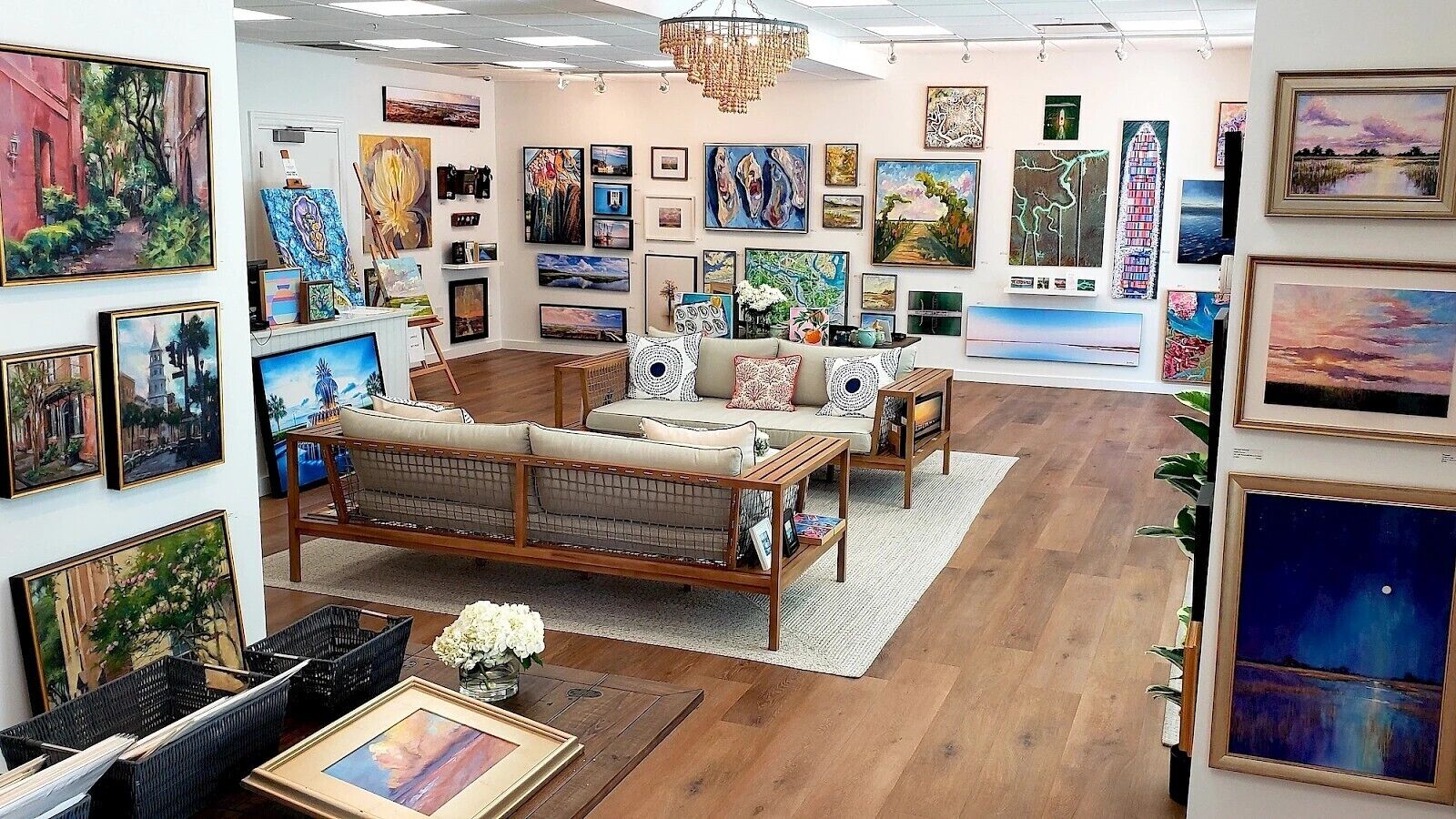 An art gallery with a sofa, chairs, and various paintings on the walls.
