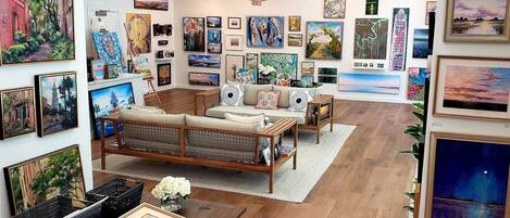 An art gallery with a sofa, chairs, and various paintings on the walls.