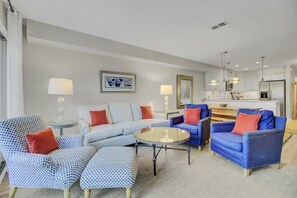 A modern living room with a sofa, armchairs, a coffee table, and a kitchen in the background. - Wild Dunes Vacation Condos 3&4 Bedrooms (Isle of Palms)
