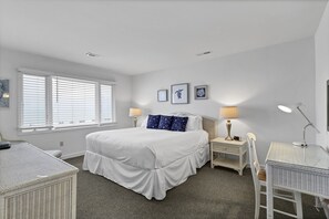 A bedroom with a bed, bedside tables, a chair, a desk, and a window with blinds. - Wild Dunes Vacation Condos 3&4 Bedrooms (Isle of Palms)