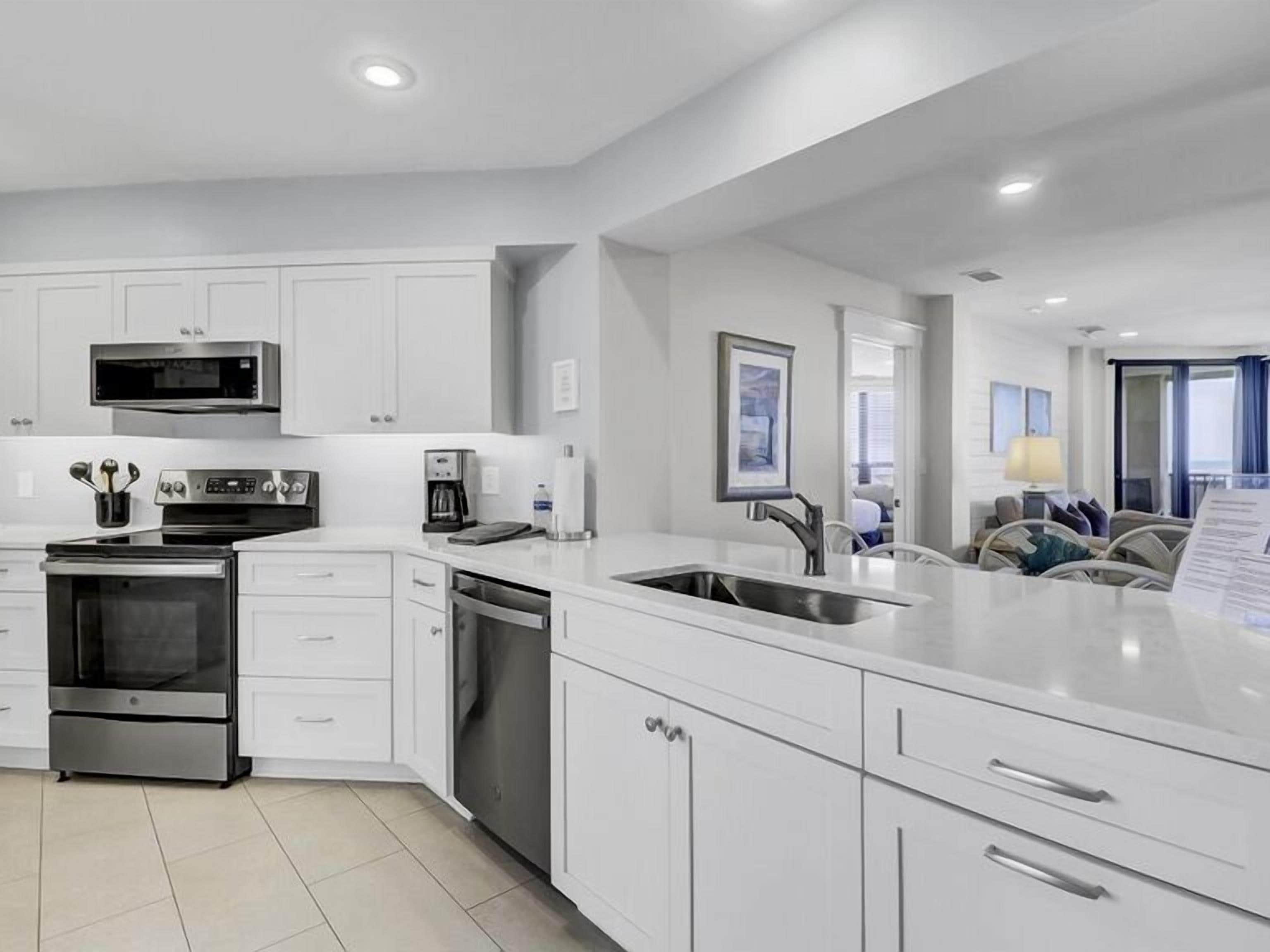 A modern kitchen with white cabinetry, stainless steel appliances, and a central island with a sink.
