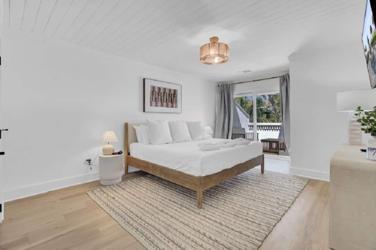Un dormitorio con una cama de madera, una lámpara de noche, una alfombra e iluminación en el techo.