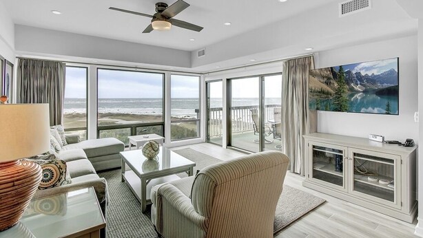 A spacious living room with a large TV, comfortable seating, and a balcony with a scenic view. - Wild Dunes Vacation Condos 3&4 Bedrooms (Isle of Palms)