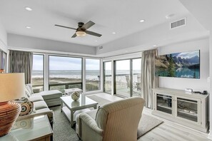 A spacious living room with a large TV, comfortable seating, and a balcony with a scenic view. - Wild Dunes Vacation Condos 3&4 Bedrooms (Isle of Palms)