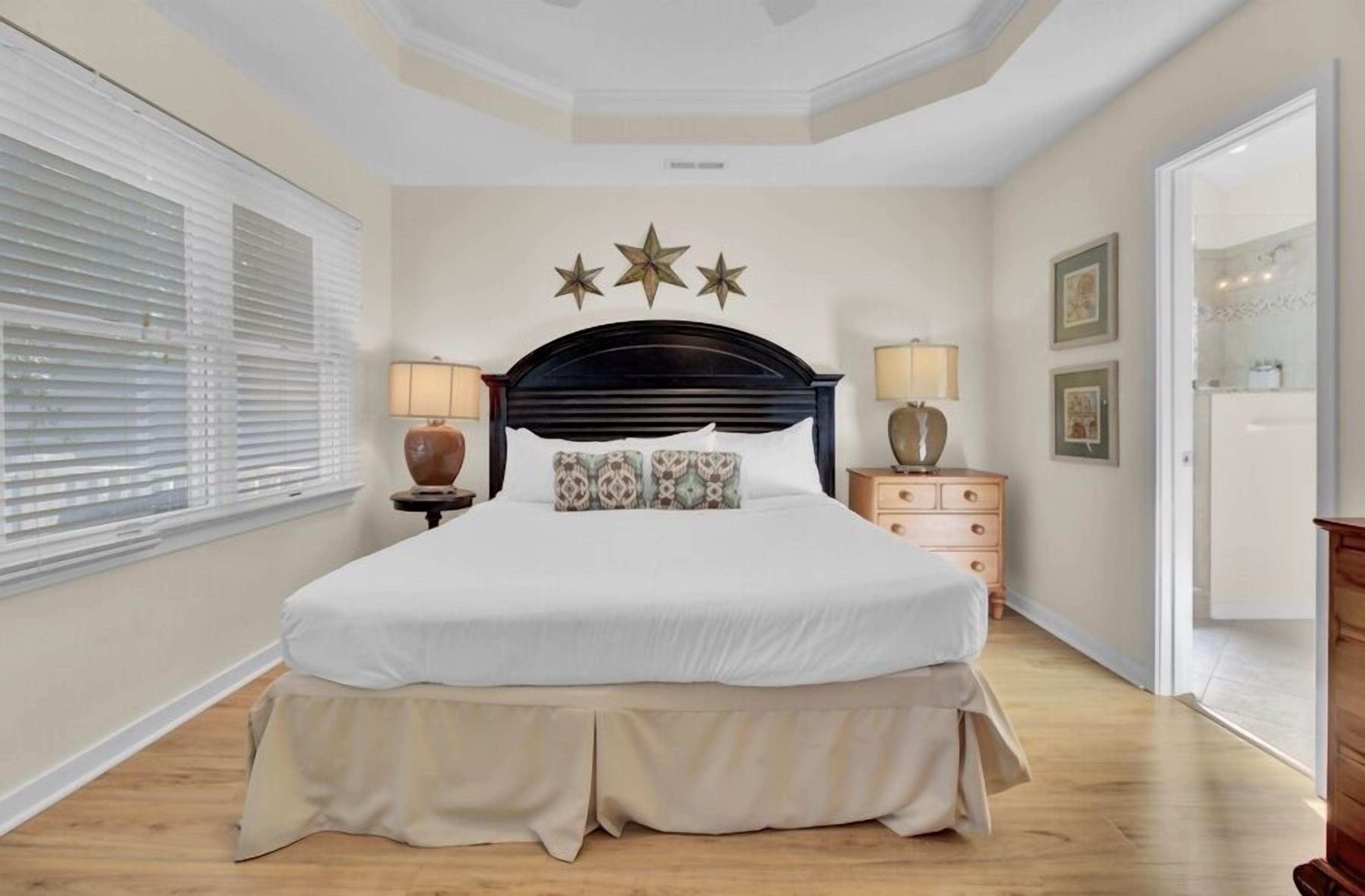 A bedroom with a bed, bedside lamps, a dresser, and a wall with star decorations.